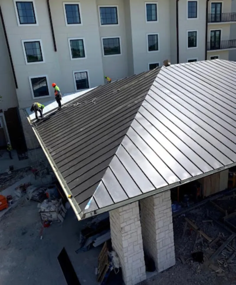 Crew installing standing seam metal roof panels on a commercial project in Shawano